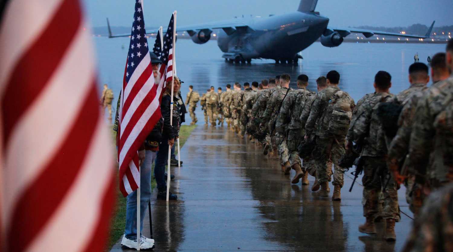 FILE - In this Saturday, Jan. 4, 2020, file photo, this photo provided by the U.S. Army, paratroopers assigned to 1st Brigade Combat Team, 82nd Airborne Division walk as they prepare equipment and load aircraft bound for the U.S. Central Command area of operations from Fort Bragg, N.C. A push led by pro-Iran factions to oust U.S. troops from Iraq is gaining momentum, bolstered by a Parliament vote in favor of a bill calling on the the government to remove them. But the path forward is unclear. (Spc. Hubert Delany III/U.S. Army via AP, File)